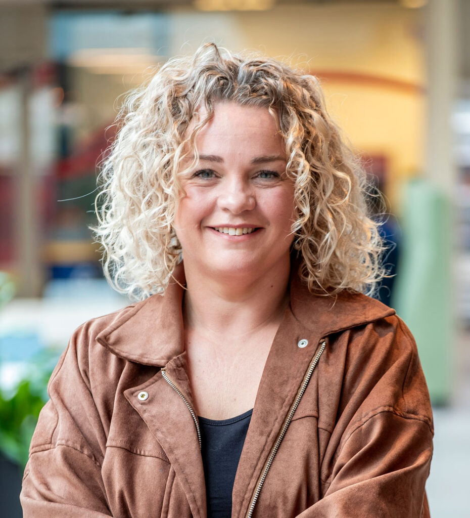 Person with curly hair, brown jacket.